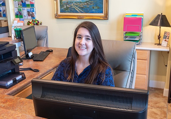 Friendly team member at dental office reception desk