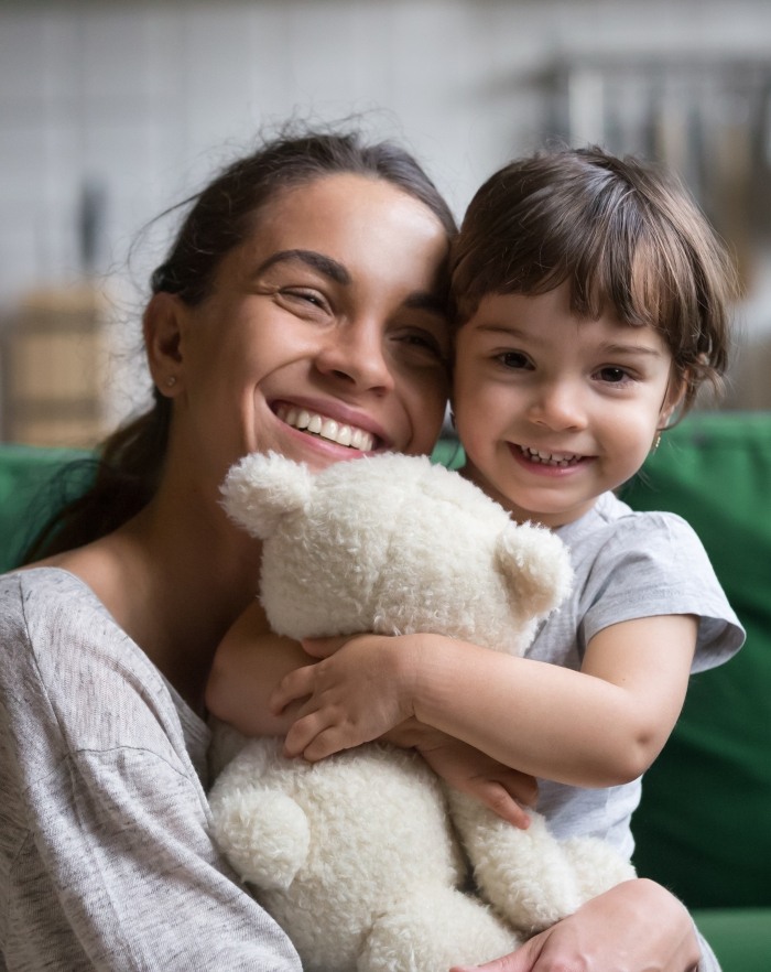 Mother holding daughter with healthy smile thanks to children's dentistry