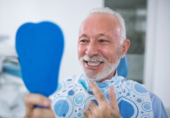 Man looking at his smile after full mouth reconstruction