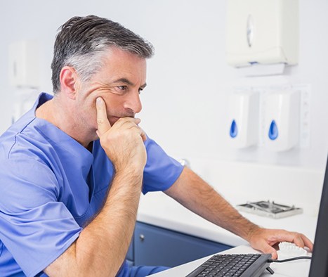 Dentist looking at computer monitor, examining results of CBCT scan