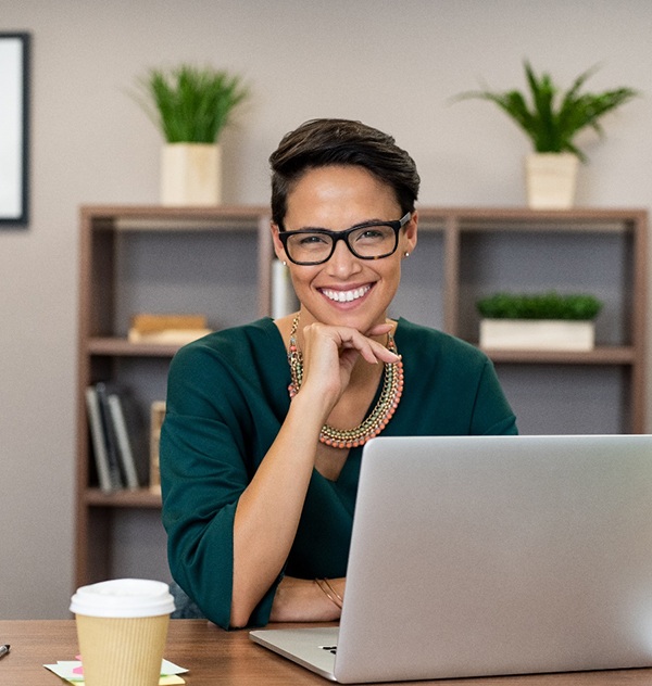 Business woman working on laptop, smiling with dental crown in New Braunfels, TX