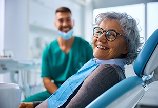 Woman with black glasses smiling in treatment chair