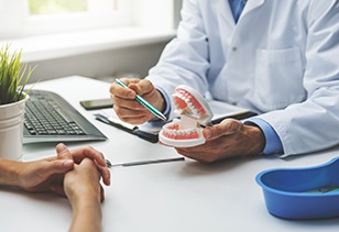 Dentist showing patient model of teeth