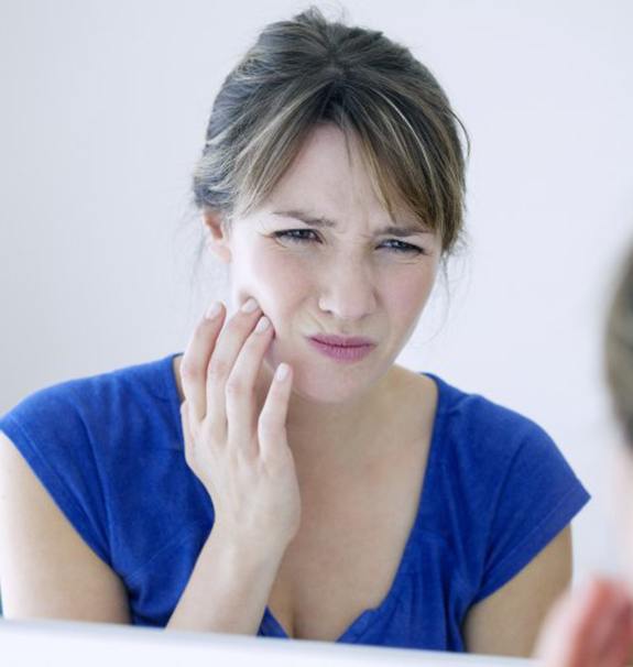 woman in blue shirt who needs emergency dentist in New Braunfels to treat toothache 