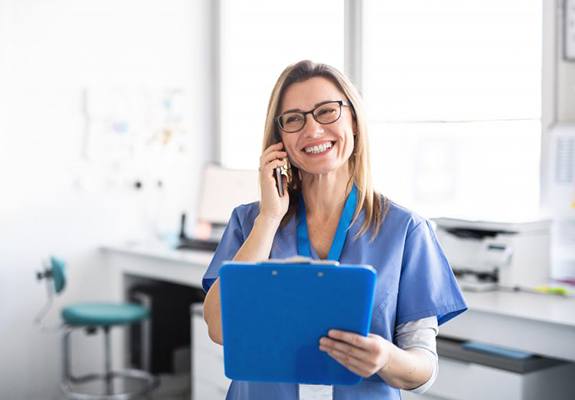 dental assistant talking on phone and holding blue clipboard 