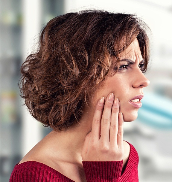 Woman in need of emergency dentistry holding jaw