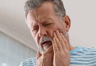 Man with lost filling holding cheek