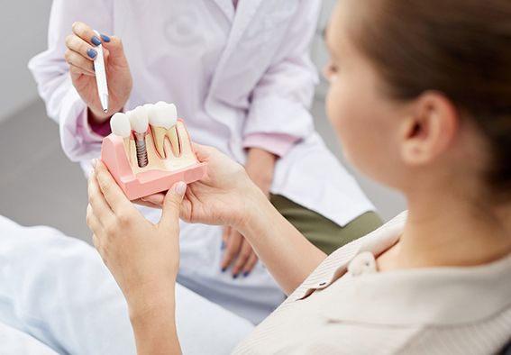 Dentist showing patient model of dental implant