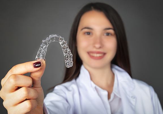 Woman holding up Invisalign tray