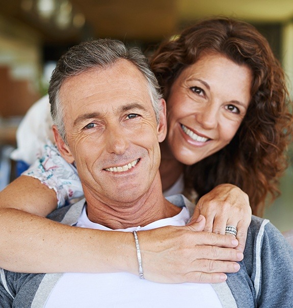 Man and woman with healthy smiles after periodontal therapy