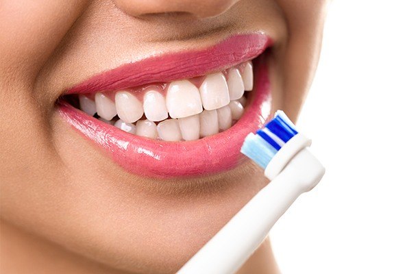 Woman brushing teeth with electric toothbrush