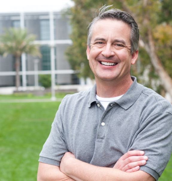 man smiling outside with arms crossed