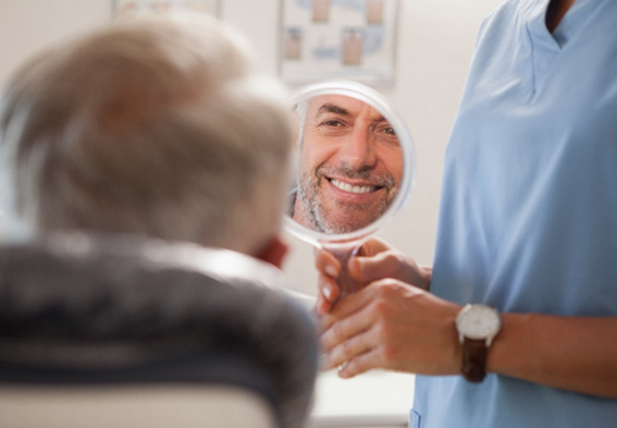 Middle-aged man looking at his smile in mirror