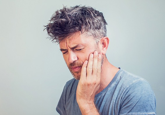 Man grimacing due to mouth pain