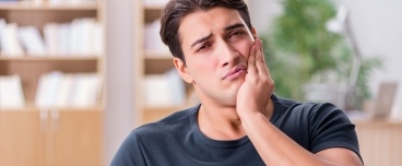 Man in need of emergency dentistry holding jaw