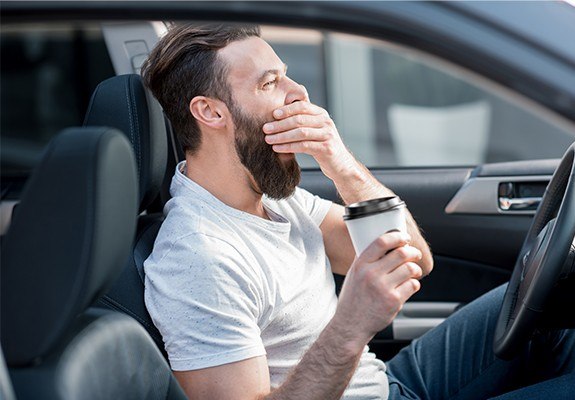 Tired man yawning behind the wheel