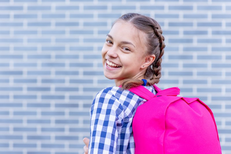 Girl with pink backpack smiling on first day of school