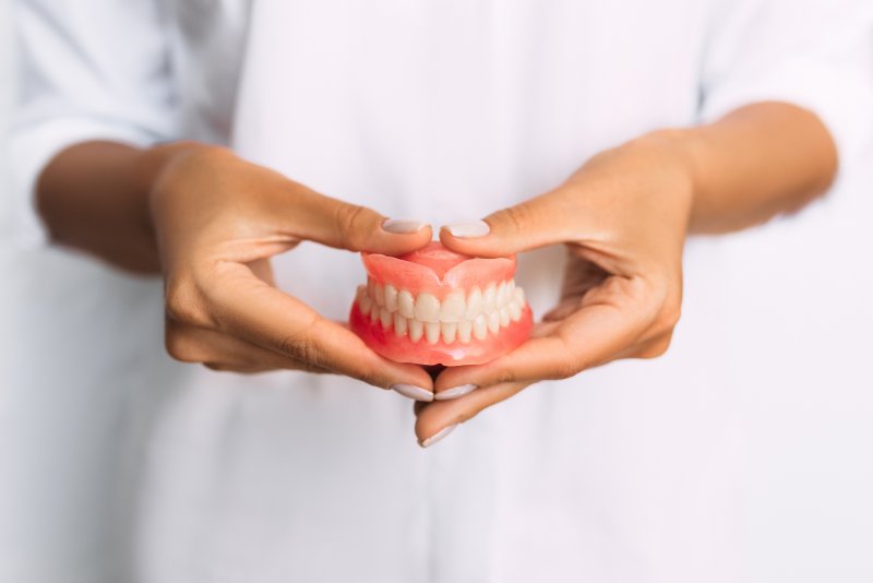 dentist holding dentures in hand