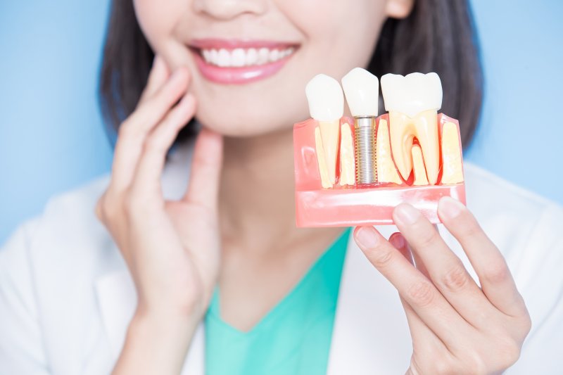 dentist smiling and showing off dental implant