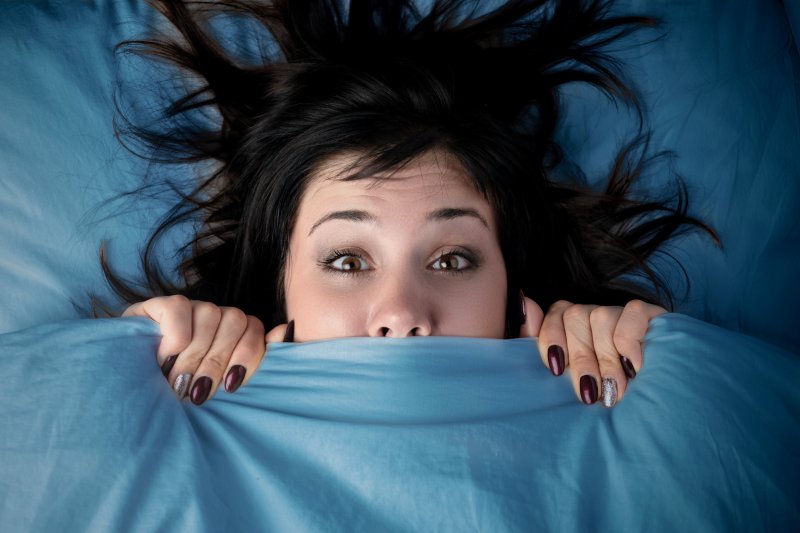 woman hiding under covers.