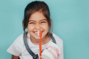 little girl smiling and brushing her teeth