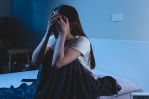 Woman sitting up in bed, waking up from a nightmare